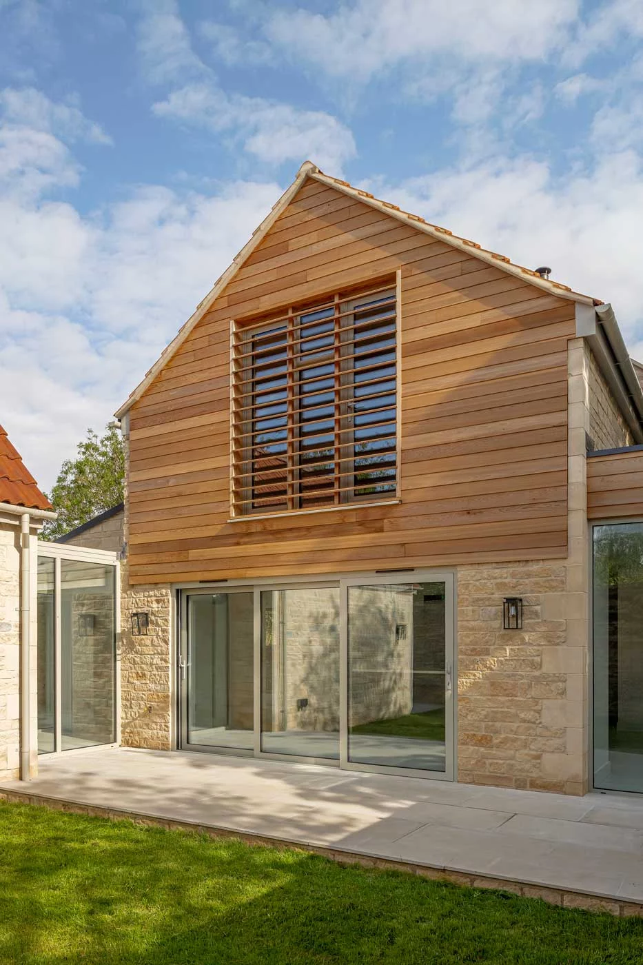 A modern cedar-clad gable section providing a contemporary contrast to the traditional stone barn.