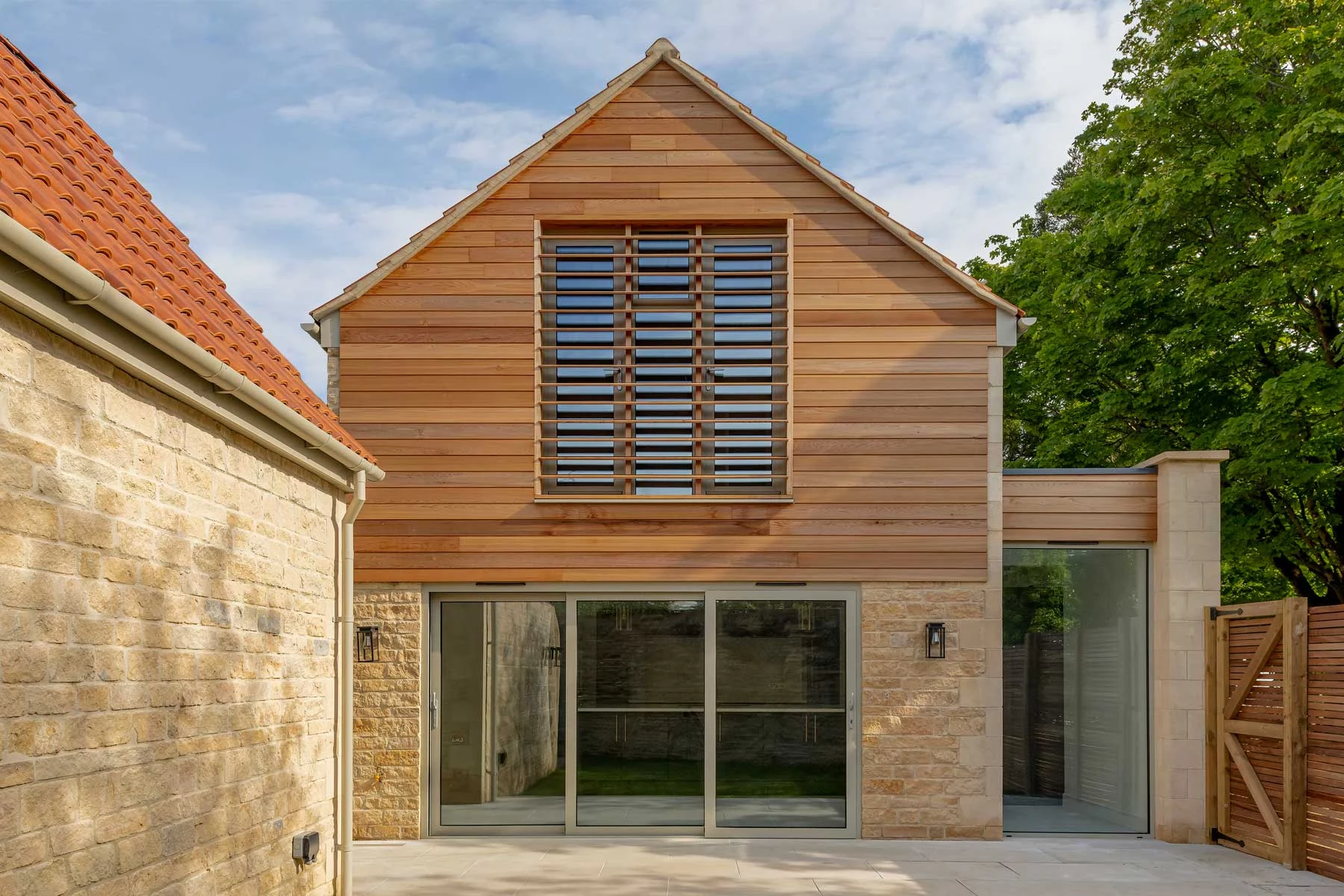 Floor-to-ceiling feature glazing integrated within a traditional stone and timber envelope.